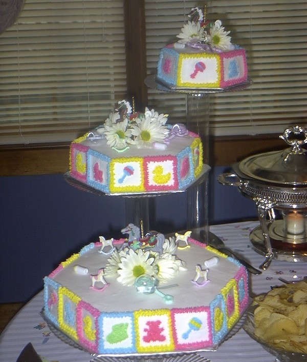 Tiered Baby Shower cake with real flowers and baby-themed decorations.